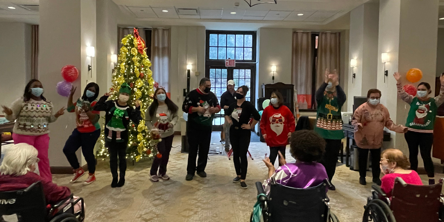 Fun holiday photo of staff members dressed in Christmas sweaters and dancing at the annual Christmas party